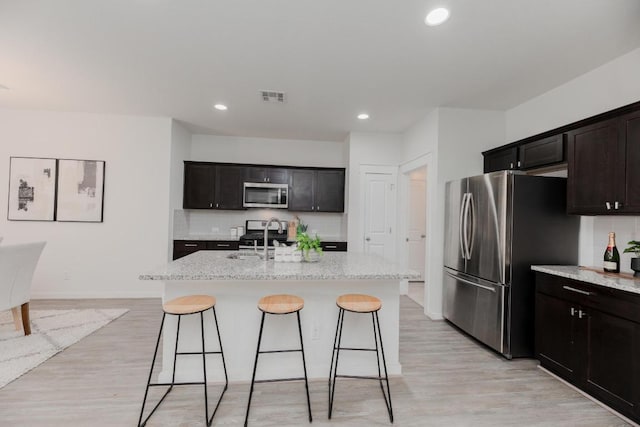 kitchen featuring visible vents, a breakfast bar area, stainless steel appliances, and decorative backsplash