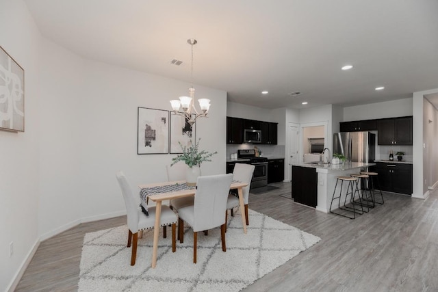 dining area featuring light wood finished floors, a chandelier, recessed lighting, and baseboards