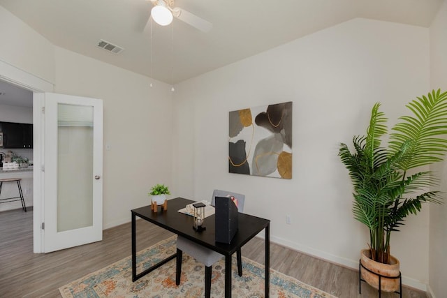 home office featuring visible vents, light wood-type flooring, ceiling fan, and vaulted ceiling