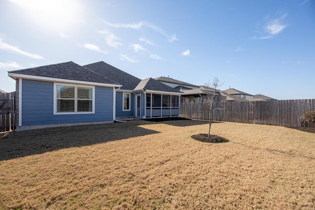 back of house with a lawn, fence, a sunroom, and roof with shingles