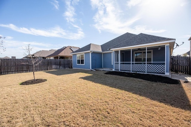 back of property with a yard, a shingled roof, a fenced backyard, and a sunroom