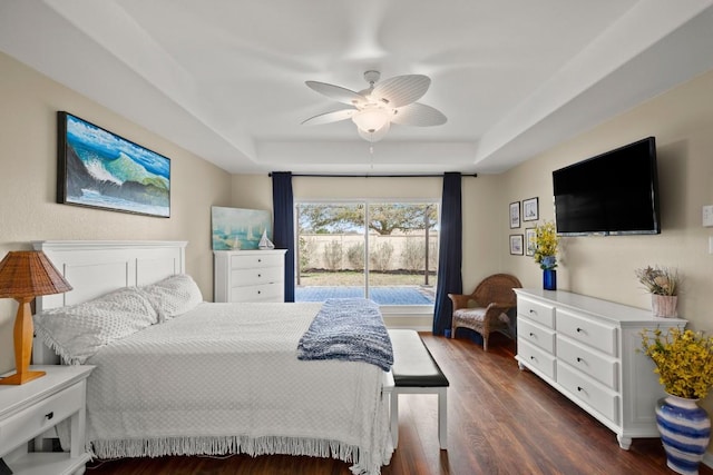 bedroom with a ceiling fan, a raised ceiling, access to exterior, and dark wood-style flooring