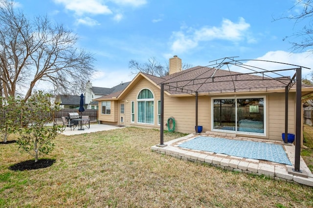 back of house with a patio area, a yard, fence, and a chimney