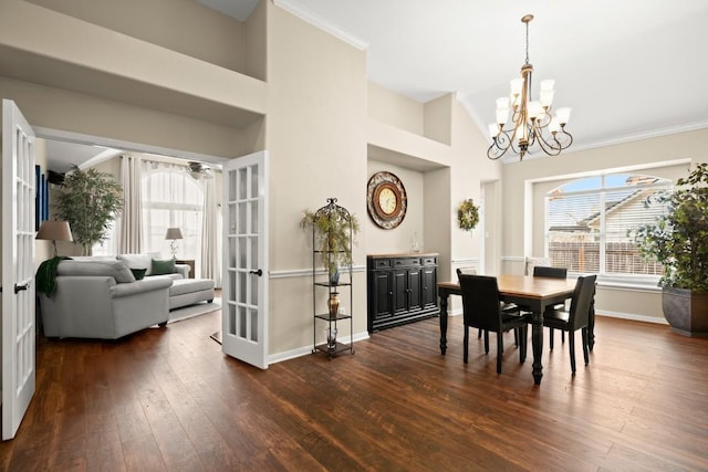 dining area featuring ceiling fan with notable chandelier, french doors, high vaulted ceiling, dark wood-style flooring, and baseboards