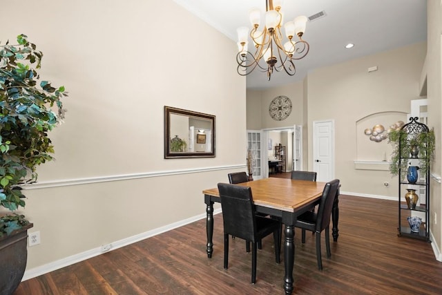 dining space featuring a towering ceiling, recessed lighting, dark wood finished floors, an inviting chandelier, and baseboards