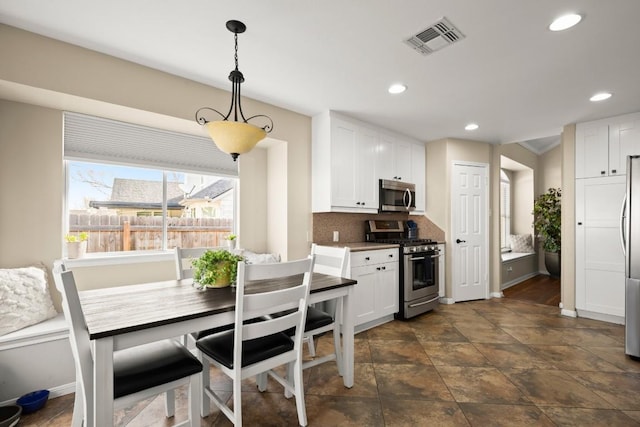 kitchen with white cabinets, stainless steel appliances, visible vents, and decorative light fixtures