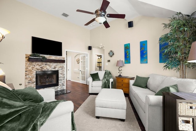 living room featuring wood finished floors, high vaulted ceiling, visible vents, a stone fireplace, and ceiling fan