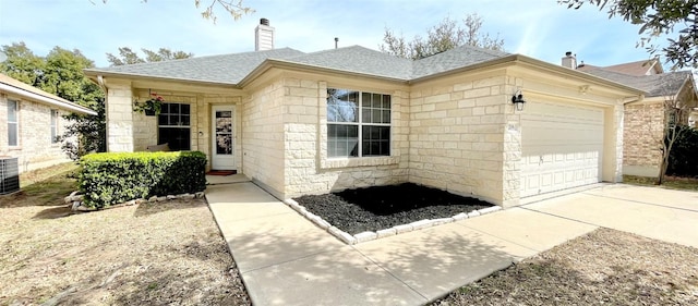 single story home with central AC, concrete driveway, an attached garage, a shingled roof, and a chimney