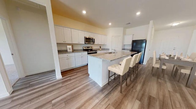 1424 Morris Loop, San Marcos, TX 78666 - kitchen featuring stainless steel appliances, a sink, white cabinetry, a breakfast bar area, and recessed lighting