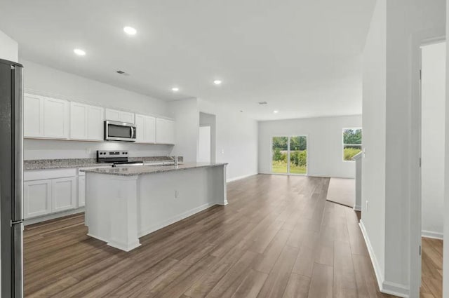 1424 Morris Loop, San Marcos, TX 78666 - kitchen with stainless steel appliances, wood finished floors, open floor plan, recessed lighting, and white cabinetry
