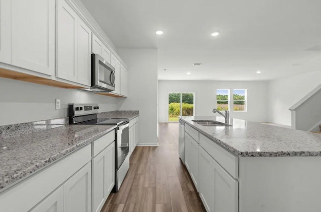1424 Morris Loop, San Marcos, TX 78666 - kitchen with appliances with stainless steel finishes, a sink, dark wood finished floors, white cabinets, and an island with sink