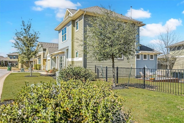 view of side of property featuring a lawn, fence, and a residential view