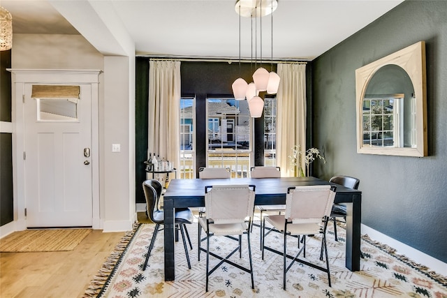 dining space featuring a textured wall, baseboards, and wood finished floors