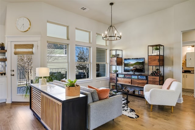 living room with a high ceiling, a notable chandelier, wood finished floors, and visible vents