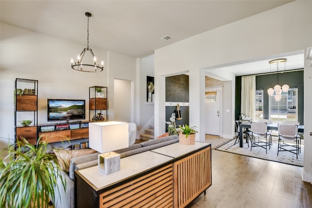 living area featuring visible vents, an inviting chandelier, wood finished floors, and stairway