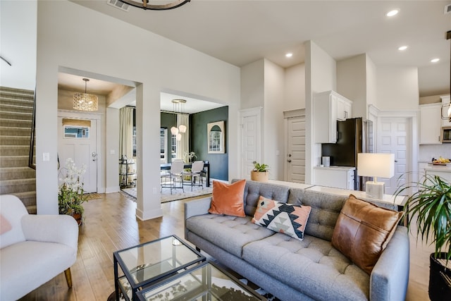 living room featuring stairs, recessed lighting, light wood finished floors, and a chandelier