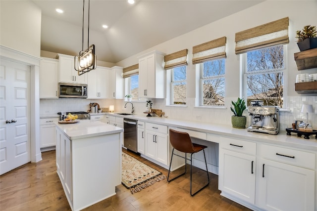 kitchen featuring backsplash, lofted ceiling, light wood-style flooring, appliances with stainless steel finishes, and white cabinets