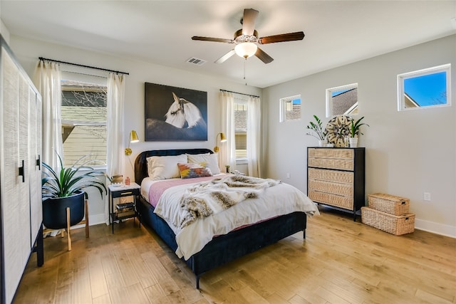 bedroom featuring light wood-style flooring, multiple windows, baseboards, and visible vents