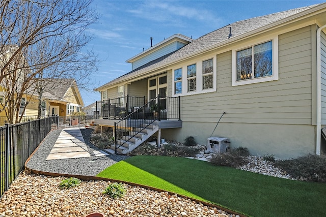 back of property featuring a yard, a shingled roof, and fence