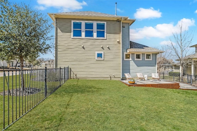 rear view of property featuring a patio area, a lawn, a fenced backyard, and roof with shingles