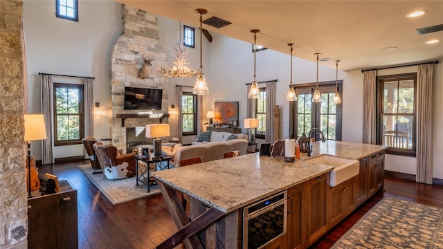 kitchen featuring light stone countertops, visible vents, a fireplace, a sink, and dark wood-type flooring