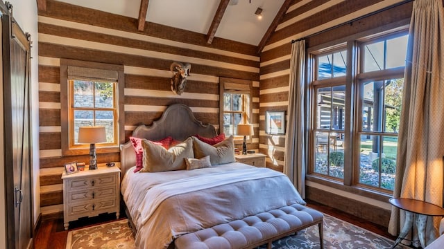 bedroom with lofted ceiling with beams, a barn door, and multiple windows