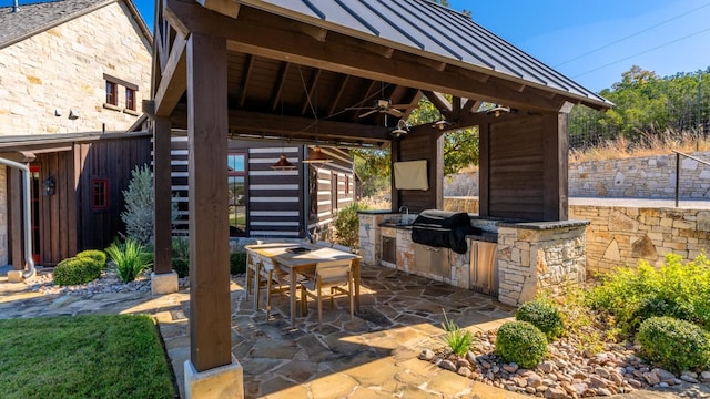 view of patio with exterior kitchen, outdoor dining area, ceiling fan, a gazebo, and grilling area