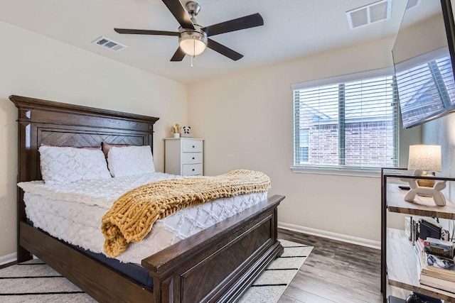 bedroom featuring ceiling fan, wood finished floors, visible vents, and baseboards