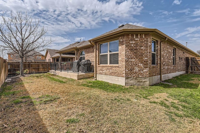 rear view of house with a patio, a yard, a fenced backyard, and brick siding