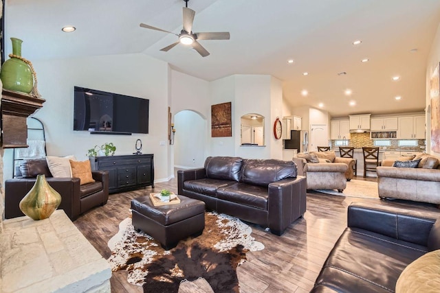 living area with wood finished floors, recessed lighting, arched walkways, ceiling fan, and vaulted ceiling