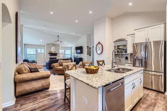 kitchen featuring vaulted ceiling, wood finished floors, appliances with stainless steel finishes, and a sink