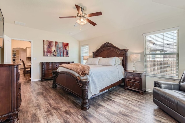 bedroom with vaulted ceiling, wood finished floors, arched walkways, and baseboards