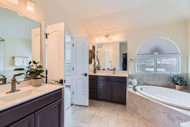 full bath featuring tile patterned flooring, two vanities, a garden tub, and a sink