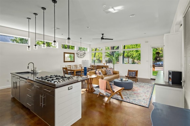 kitchen featuring dark countertops, stainless steel gas stovetop, concrete floors, and a sink