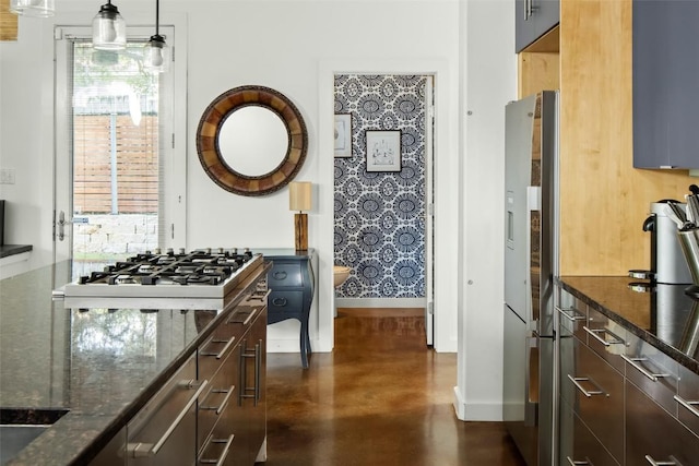 kitchen with dark stone counters, baseboards, finished concrete flooring, and freestanding refrigerator