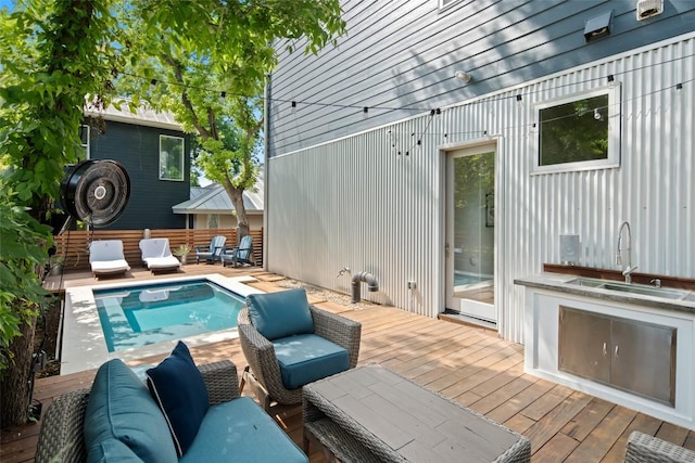 view of pool with a sink, an outdoor living space, and a deck