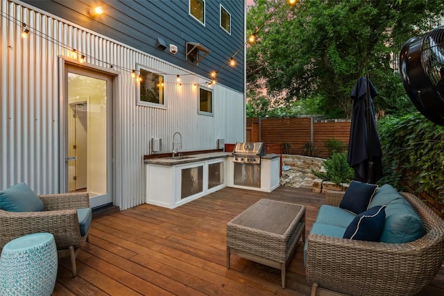 wooden terrace featuring an outdoor living space, fence, area for grilling, a grill, and a sink