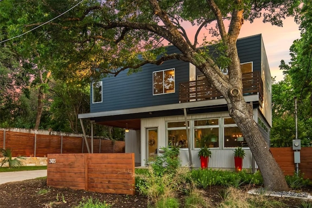 rear view of property featuring a balcony and fence