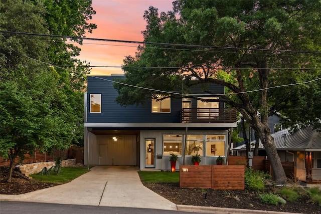 view of front of home with concrete driveway and a balcony