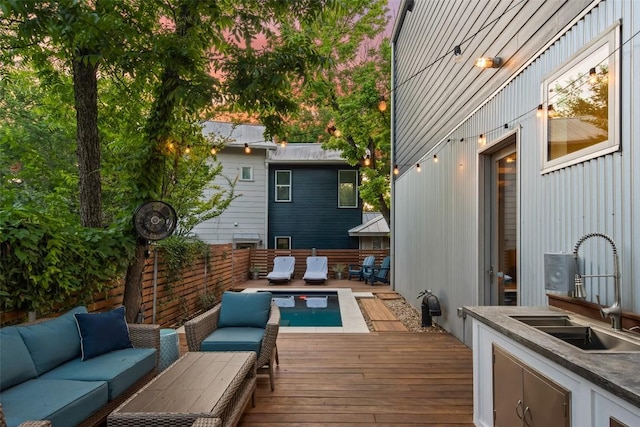 exterior space featuring a pool, fence, outdoor lounge area, a deck, and a sink