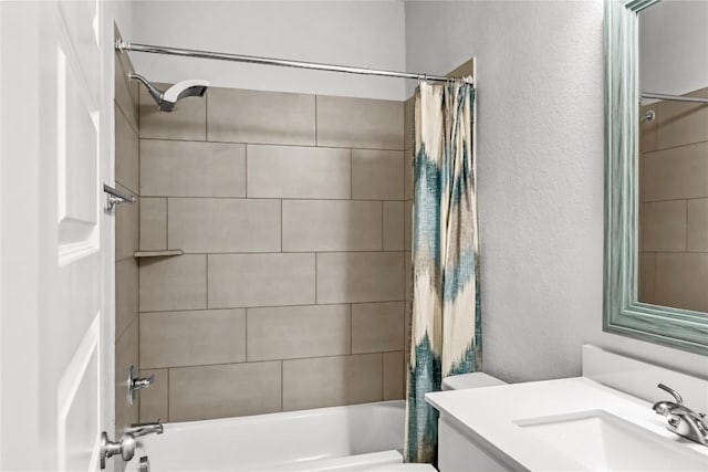 full bathroom with vanity, toilet, a textured wall, and shower / bath combo