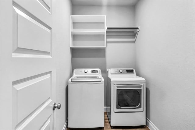 laundry room with baseboards, independent washer and dryer, wood finished floors, and laundry area