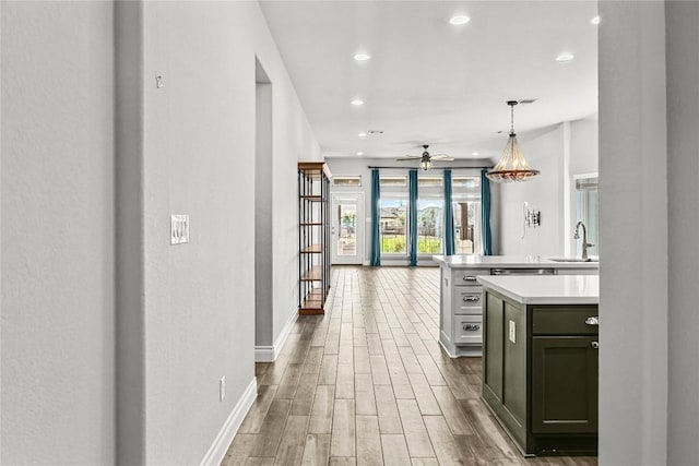 kitchen with wood finished floors, ceiling fan, a sink, light countertops, and open floor plan