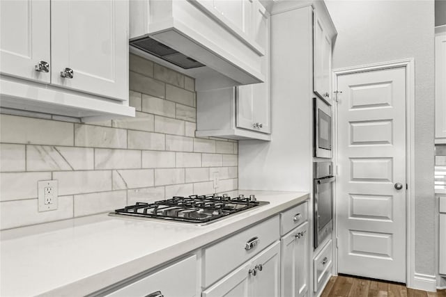 kitchen with premium range hood, decorative backsplash, appliances with stainless steel finishes, and light countertops