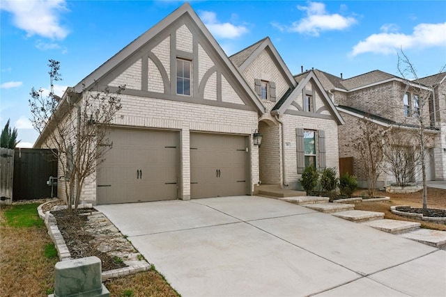 view of front of property featuring brick siding, an attached garage, driveway, and fence