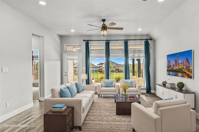 living room featuring wood finished floors, a ceiling fan, and baseboards