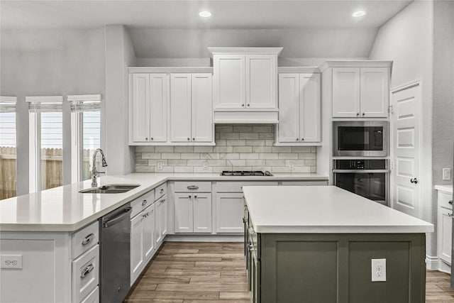 kitchen featuring a sink, appliances with stainless steel finishes, wood finished floors, and light countertops