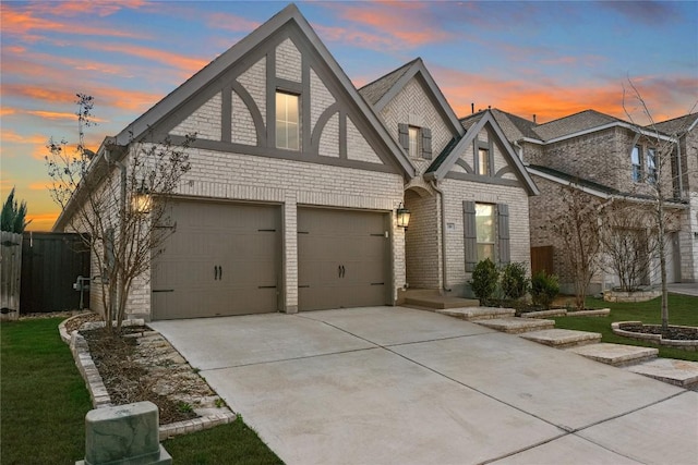 view of front facade featuring brick siding, driveway, a garage, and fence