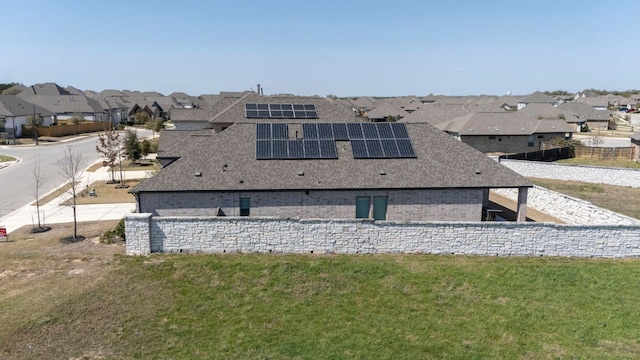 exterior space with solar panels, a lawn, a residential view, and roof with shingles