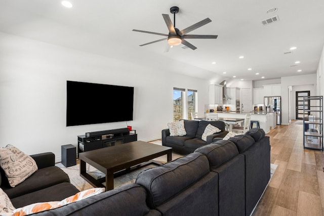 living area with light wood-type flooring, visible vents, a ceiling fan, and recessed lighting